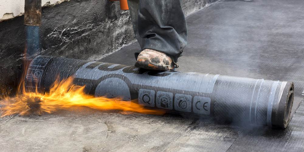 worker while burning the waterproof membrane on a roof
