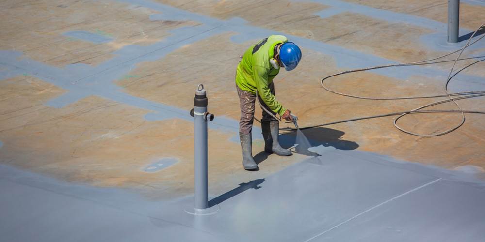 working applying SPF roof coating with a spray gun