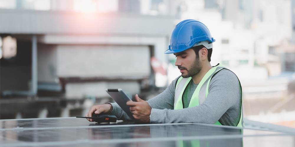 engineer on roof looking at a tablet