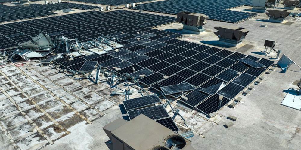 aerial view of damaged solar panels mounted on industrial building roof