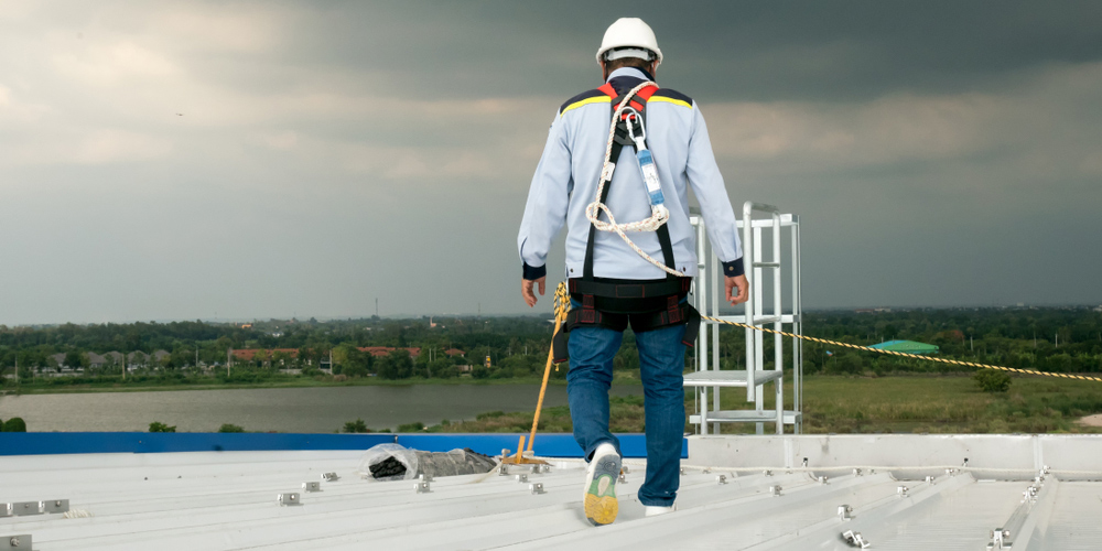 construction engineer wearing safety harness inspecting metal roofing